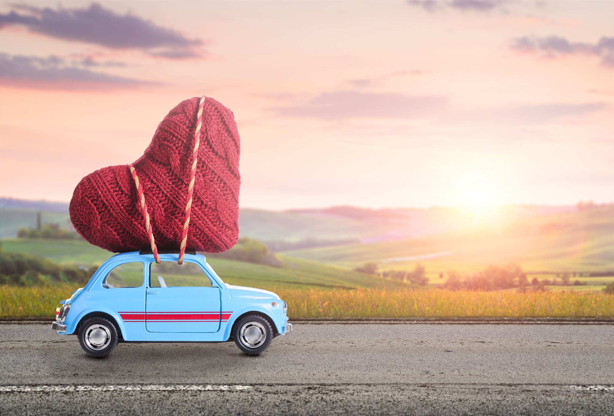 A-blue-retro-toy-car-with-a-knitted-heart-tied-on-its-roof